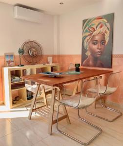 a table with chairs and a painting of a woman at Ático dúplex - 1ª Linea playa in Adra