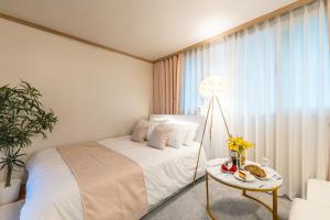 a bedroom with a white bed and a table with flowers at 홍대 골든스테이 in Seoul