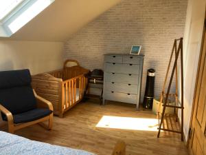 a bedroom with a crib and a dresser and a chair at Alte Gärtnerei in Blankenburg