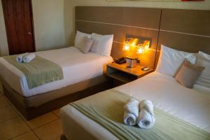 a hotel room with two beds with towels on them at Hotel El Guajataca in Quebradillas
