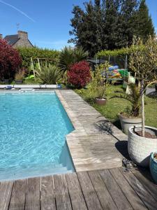 a swimming pool with a wooden deck next to a yard at Chez Audrey & Bastien in Dinan