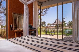 a bedroom with a bed and a large window at Casa del Toro Luxury Ranch in Nguékokh