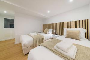 two beds in a room with white walls and wood floors at Santo Wellness Villa by Mth in Santo António da Serra