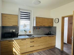 a kitchen with wooden cabinets and a sink and a window at Too Apartment Lipno in Černá v Pošumaví +15 photos