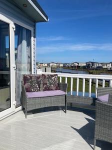 a balcony with two chairs and a view of the water at The Blue Beachcomber in Chapel Saint Leonards