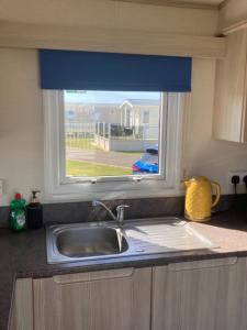 a kitchen counter with a sink and a window at The Blue Beachcomber in Chapel Saint Leonards +28 photos