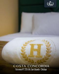 a bed with a white towel with a gold crest on it at Costa Concordia in Chiclayo