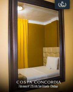 a mirror reflecting a bed with a yellow curtain at Costa Concordia in Chiclayo