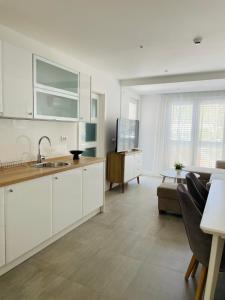 a kitchen with white cabinets and a living room at Apartmani Villa Antea in Klek