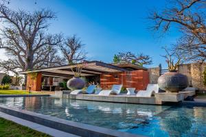 a pool with white chairs in front of a building at Casa del Toro Luxury Ranch in Nguékokh