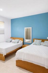 two beds in a room with a blue wall at Aquitania in Rincón