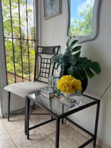 a glass table with a vase of flowers on it at Cerca de Aeropuerto , bleseed house in Monte Adentro