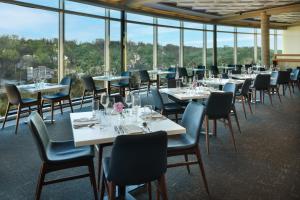 a dining room with tables and chairs and windows at The Fontaine in Kansas City