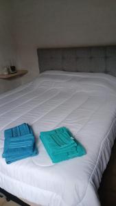 a white bed with two blue towels on it at Refugio del Limonero - Colonial y Cercano in Córdoba