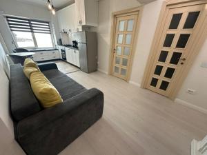 a living room with a black couch and a kitchen at Fancy Bonjour - modern apartment in Iaşi