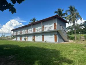 a large white building with a grass yard at Hotel e Pousada Martini in Sorriso