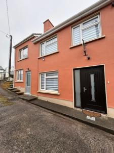 a orange house with a black door on a street at Colony Retreat in Dingle