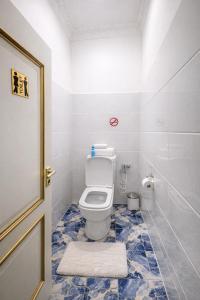 a bathroom with a toilet with a blue tiled floor at Hostel DANEXAN APA in Nukus +9 photos