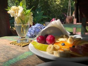 a plate of fruit on a table with a vase of flowers at Cabañas Allende Delta in Tigre