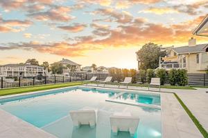 a swimming pool with two white chairs and a house at Isle Be Back in Destin