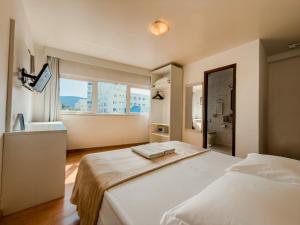 ein Schlafzimmer mit zwei Betten und einem großen Fenster in der Unterkunft Torre Sol Hotel & Eventos in Balneário Camboriú + 50 Fotos