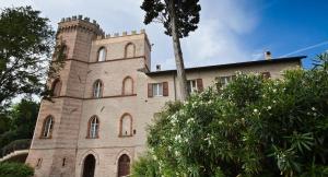un gran edificio de ladrillo con una torre encima en Castello Montegiove, en Fano