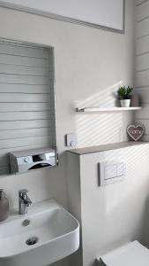 a white bathroom with a sink and a mirror at Ferienhaus Waldliebe in Grafenau +22 photos