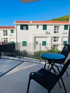 a table and a chair on a balcony with a building at Apartmani Villa Antea in Klek