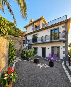 a house with two purple chairs in front of it at Skyline Villas RC in Arco da Calheta