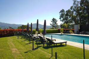 a row of chairs with umbrellas next to a pool at Casa d'Amares in Amares