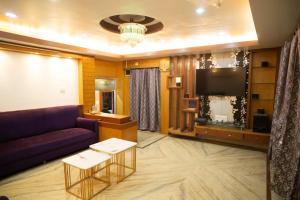 a living room with a purple couch and a flat screen tv at The Tulsi Enclave Riverside in Agartala