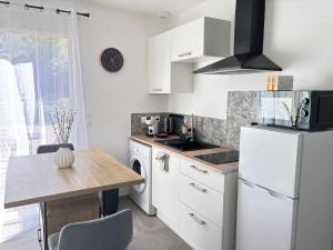 a kitchen with a white refrigerator and a table at la pause soleil, villa climatisée, avec jardin et parkings privés, à 5 mn de la mer, au calme in Martigues