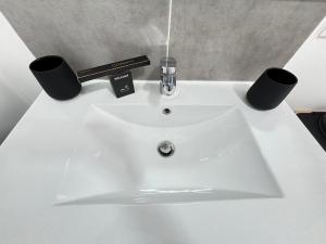 a white sink with two black cups on it at la pause soleil, villa climatisée, avec jardin et parkings privés, à 5 mn de la mer, au calme in Martigues +13 photos