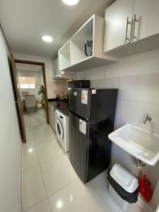 a small kitchen with a black refrigerator and a sink at Edificio Juan XXIII - 2 Dormitorios - Zona Shopping Del Sol in Asunción