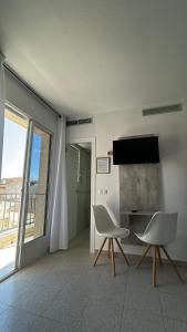 a living room with two white chairs and a television at Hotel Congra in Pilar de la Horadada