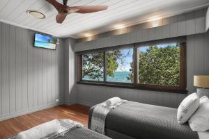 a bedroom with a ceiling fan and a large window at Dolphins at Sunset in Amity Point