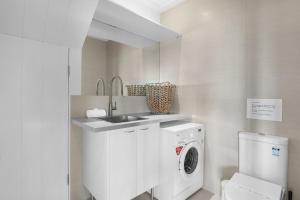 a white bathroom with a sink and a washing machine at Dolphins at Sunset in Amity Point +10 photos