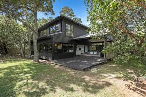 a black house with a porch and trees at Dolphins at Sunset in Amity Point