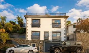 a white house with a car parked in front of it at Skyline Villas Room in Calheta