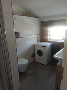 ein kleines Badezimmer mit Waschmaschine und Toilette in der Unterkunft Auszeitbude Mudau, FeWo auf 48 m2 in Mudau + 22 Fotos