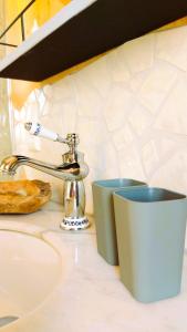 a sink with a toothbrush and two cups on a counter at Boutique Loft "Mrs Green" im Thayatal, Tiny Haus in Drosendorf Stadt