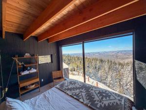 a bedroom with a bed and a large glass window at Montagne le Maelström in Lac-Beauport +265 photos