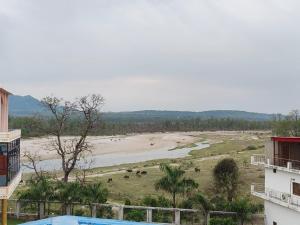 a view of a river with animals in a field at The Hills & Waves in Rishīkesh