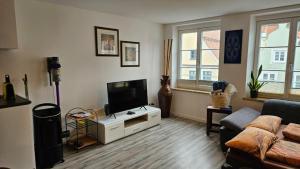 a living room with a couch and a television at Studio - Charmant, Gemütlich & Zentral in Landsberg am Lech +6 photos