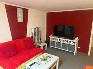 a living room with a red couch and a flat screen tv at Gästehaus Graupner in Hainichen