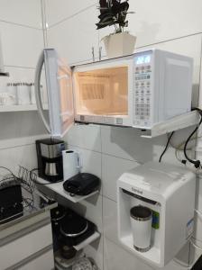 a kitchen with a microwave and a coffee maker at Casa Paraíso Piscina Aquecida e Pet Friendly in Sinop