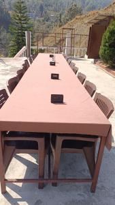 a large wooden table with chairs around it at Rajvin Heavens Resort in Bhīm Tāl