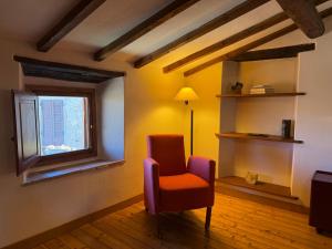 a living room with a red chair and a window at Campanile N1 in Montemerano