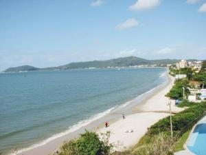 a beach with people on the sand and the water at Pousada Centralmar in Florianópolis