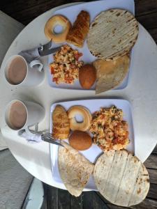 two plates of food with eggs and bread on a table at Glamping Paraiso in San Roque